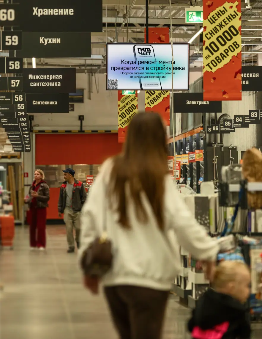 Покупатели и рекламный экран в гипермаркете Дом Лента